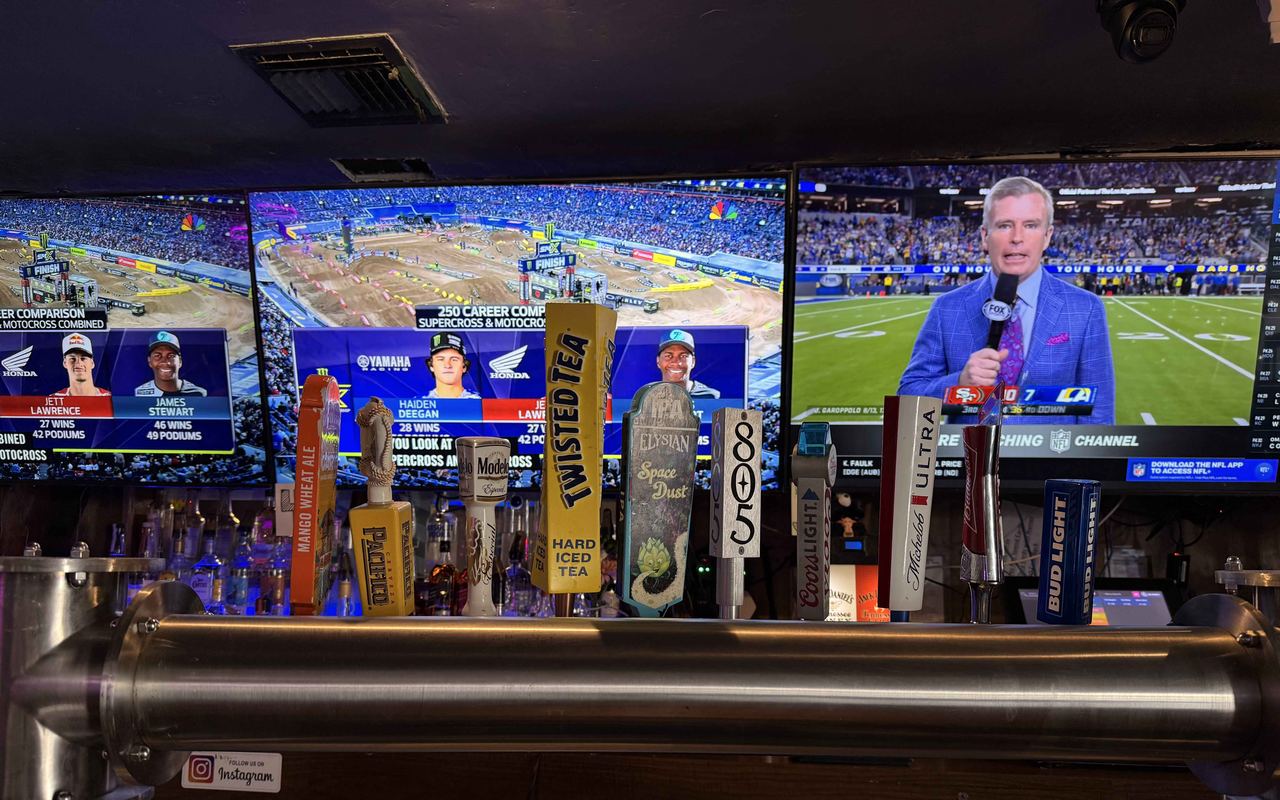 TVs over the tap row at Dingers Sports Bar in San Bernardino, showing motocross and NFL coverage.